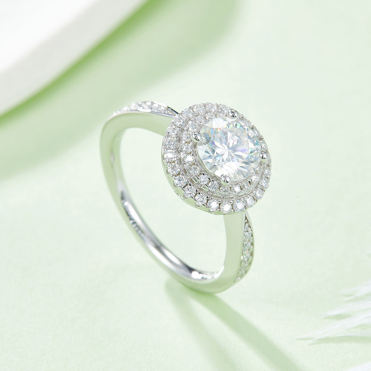 CARISSIE round moissanite halo engagement ring, side angle on green background displaying band curvature