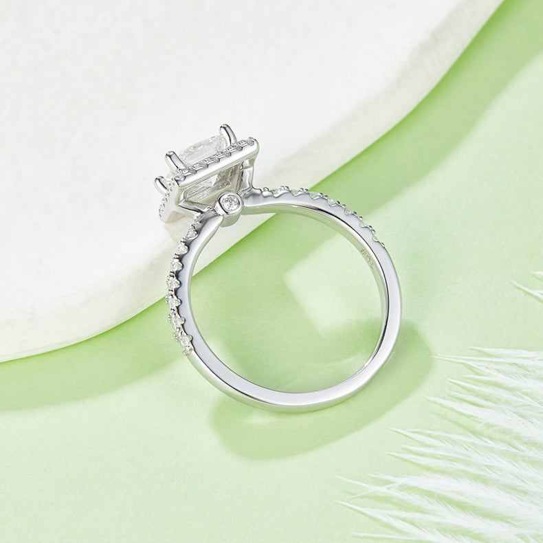 CARISSIE princess halo engagement ring, lifestyle shot on green surface showing the inner band polish and stone alignment