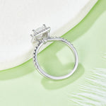 CARISSIE princess halo engagement ring, lifestyle shot on green surface showing the inner band polish and stone alignment
