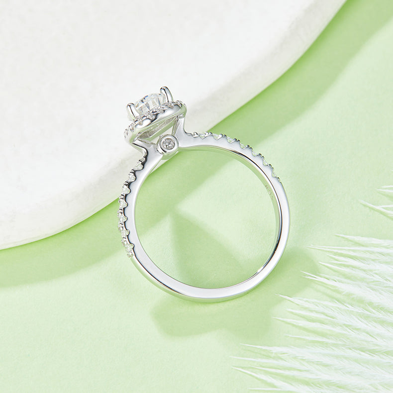 CARISSIE pear moissanite halo engagement ring, under-view on green surface showing interior metalwork