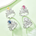 CARISSIE pear moissanite halo ring collection, flat lay of four rings with yellow, pink, blue, and white center stones