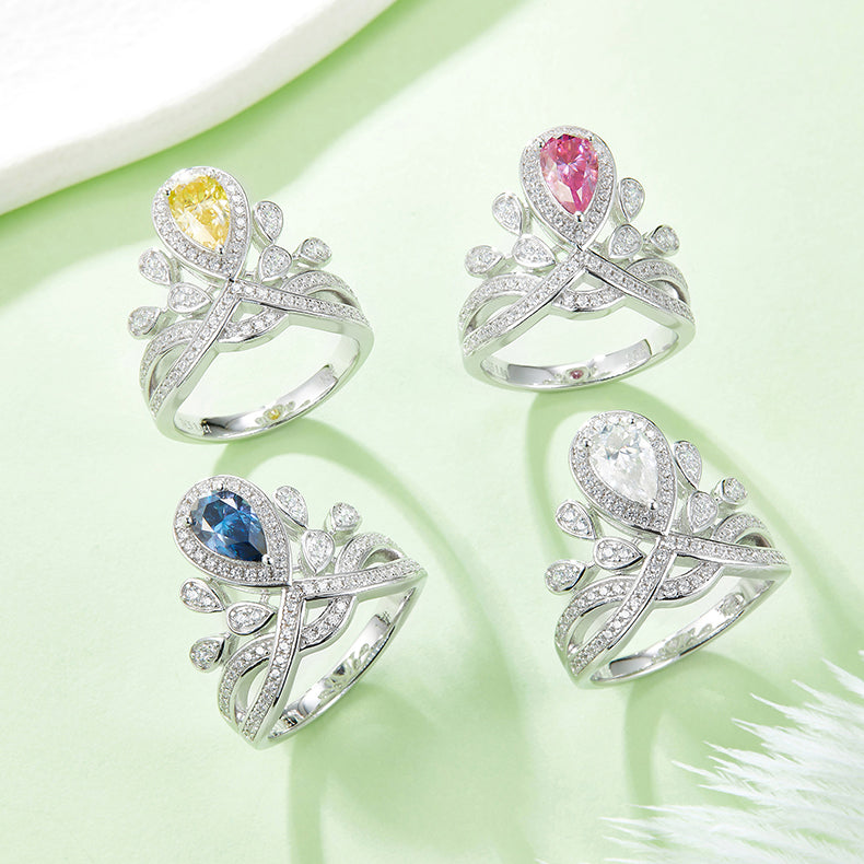 CARISSIE pear moissanite halo ring collection, flat lay of four rings with yellow, pink, blue, and white center stones