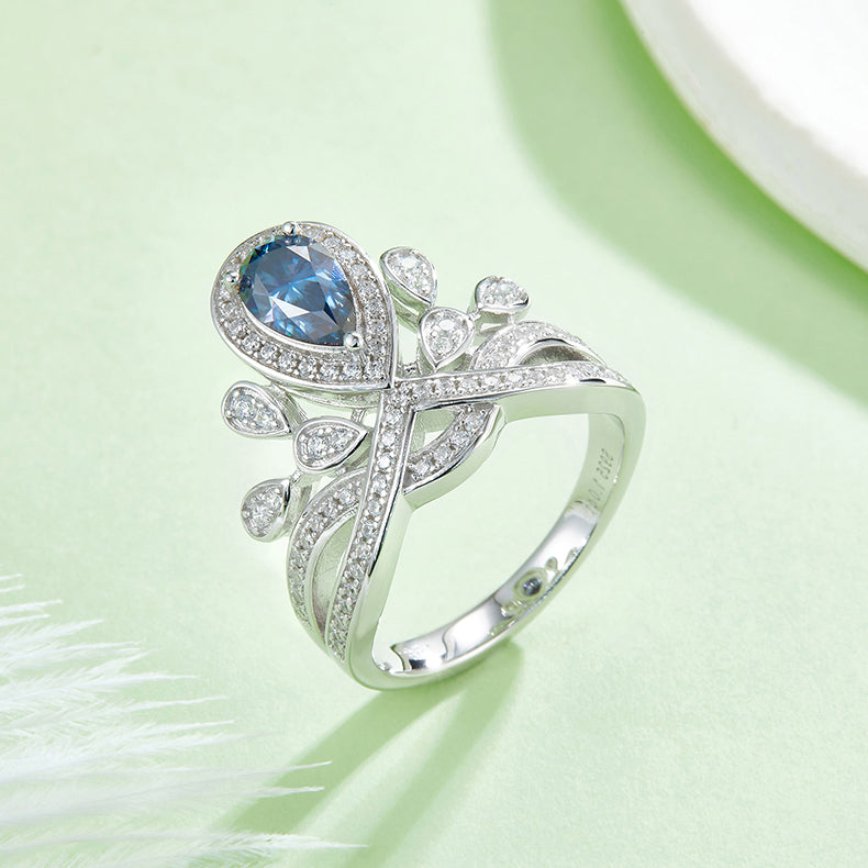 CARISSIE pear moissanite halo ring, detailed view of the blue center stone set within the nature-inspired silver design