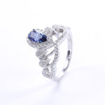 CARISSIE pear moissanite halo engagement ring, three-quarter angle showcasing a deep blue center gemstone set in silver-tone metal