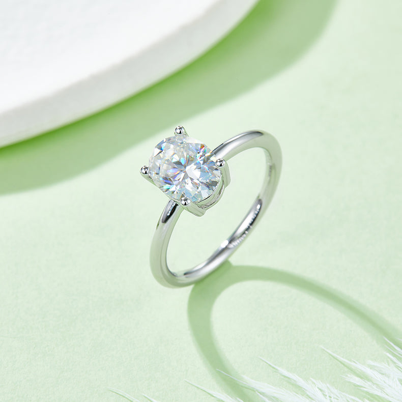 CARISSIE oval moissanite solitaire ring, lifestyle shot on a green background displaying fire and sparkle in the gemstone