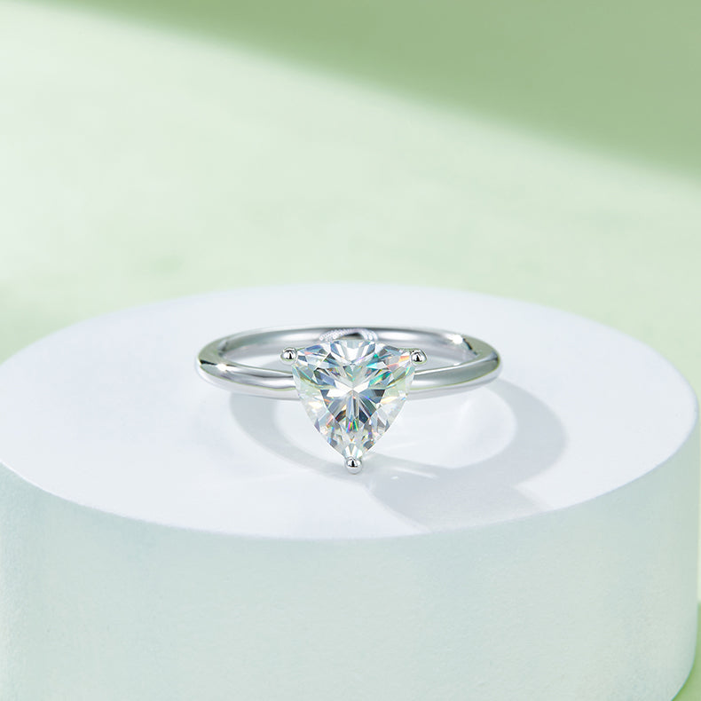 CARISSIE trillion solitaire engagement ring, elevated display on a white podium emphasizing the geometric shape and brilliance