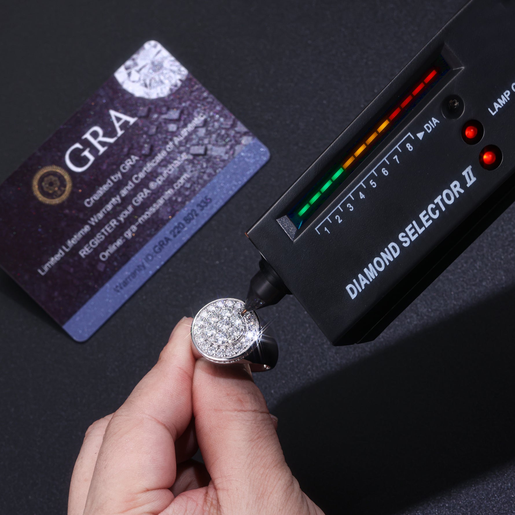 CARISSIE moissanite statement ring being tested with a diamond selector tool, verifying thermal conductivity next to an authenticity card