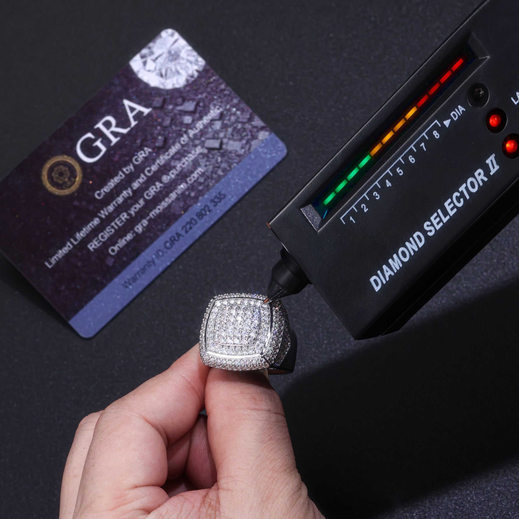 CARISSIE round moissanite statement ring being tested with a diamond selector tool next to a GRA warranty card