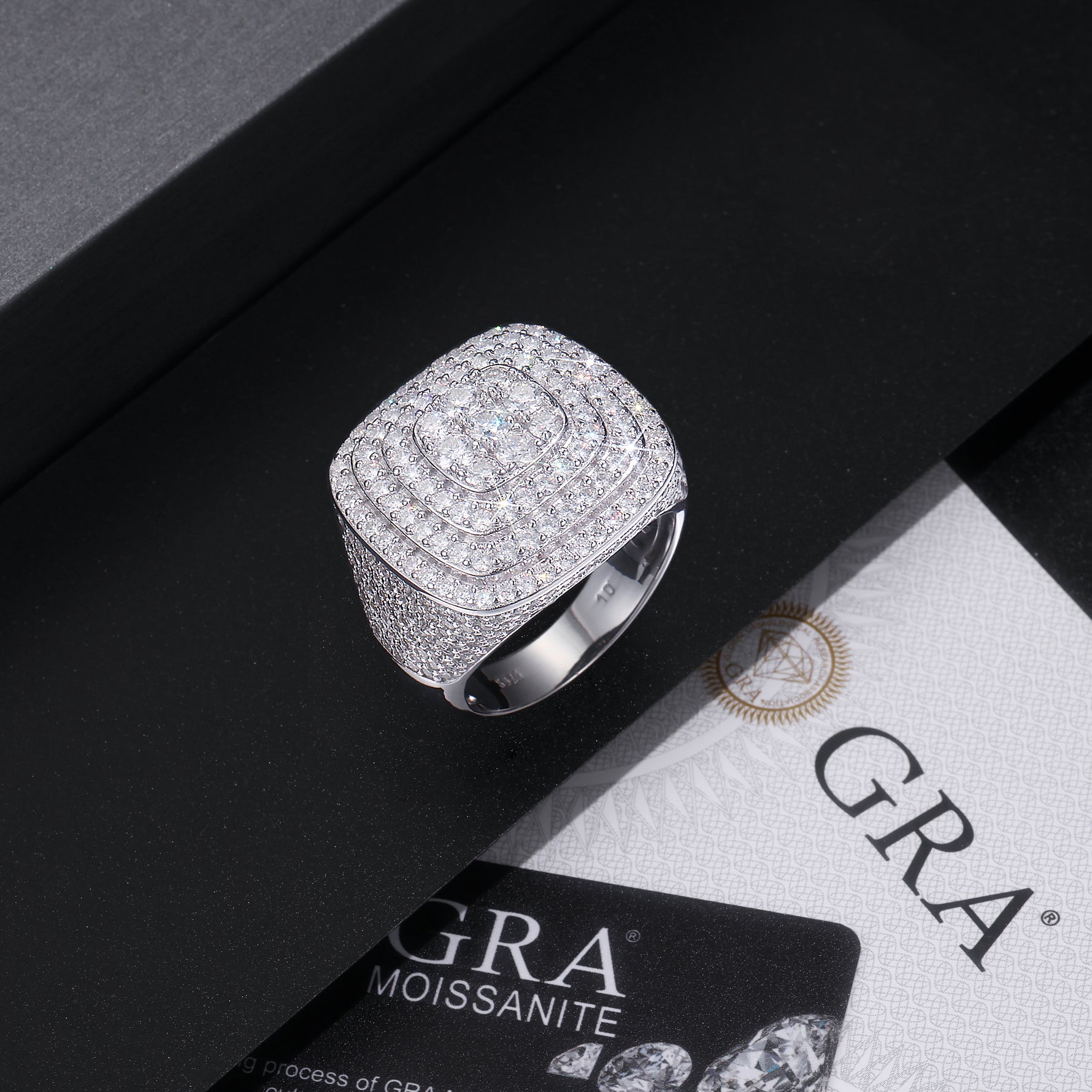 CARISSIE cushion moissanite statement ring, styled on a black surface next to a GRA moissanite certificate