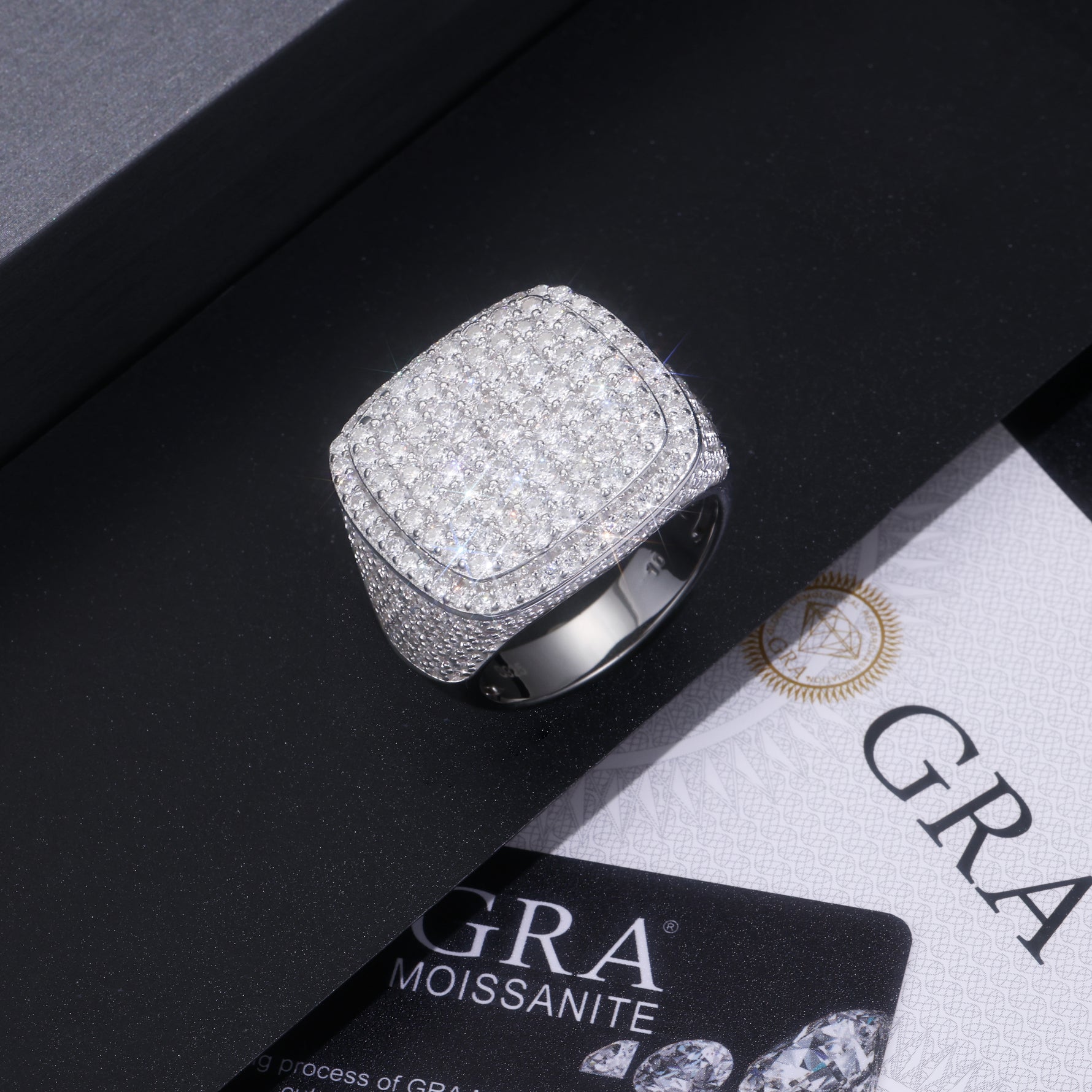 CARISSIE cushion moissanite statement ring resting on black box next to GRA certification card for authenticity verification