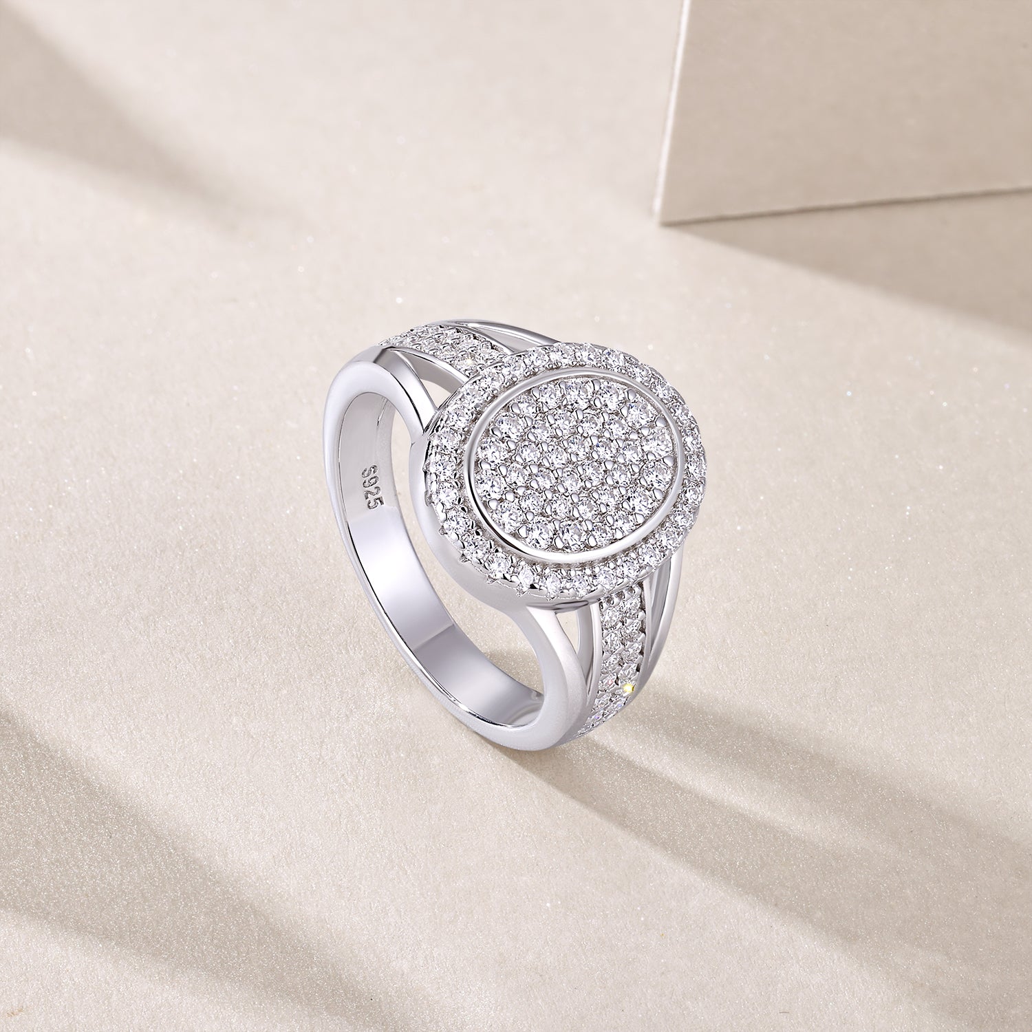 CARISSIE round moissanite halo ring, lifestyle angle on beige surface highlighting S925 stamp inside the band