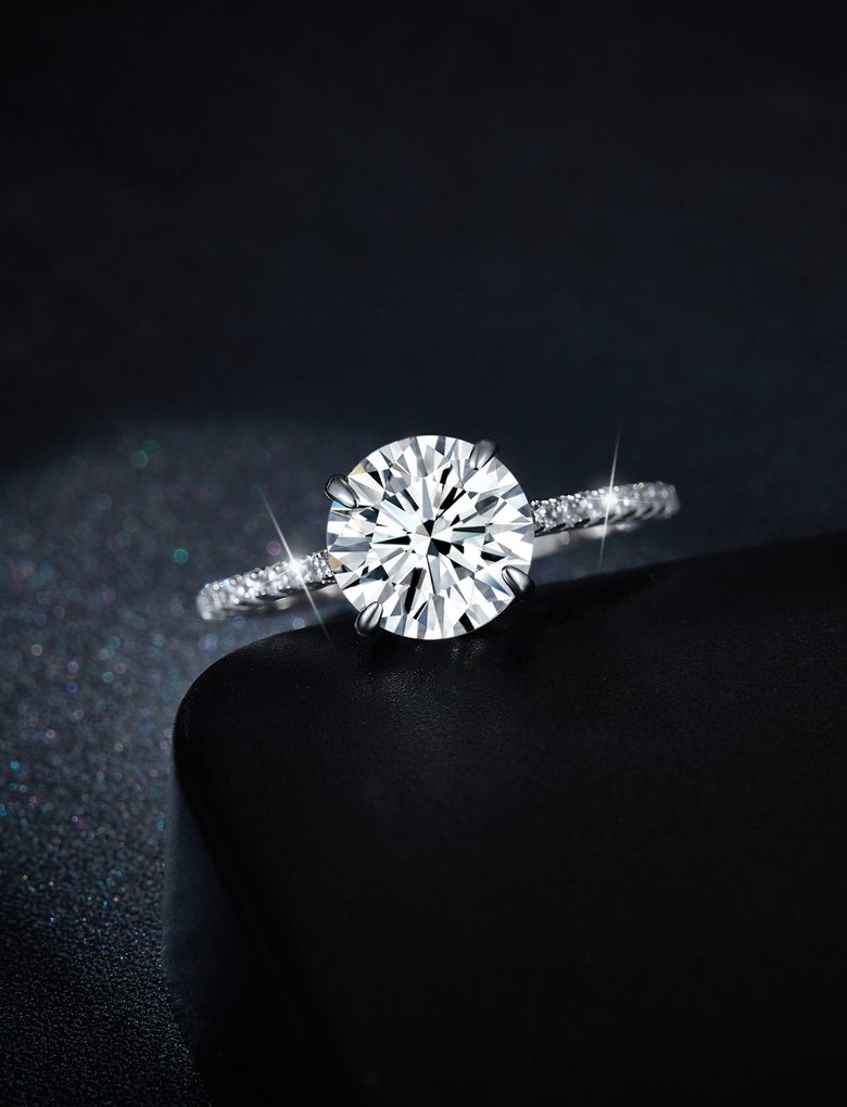 Round moissanite pavé solitaire engagement ring under a spotlight on black